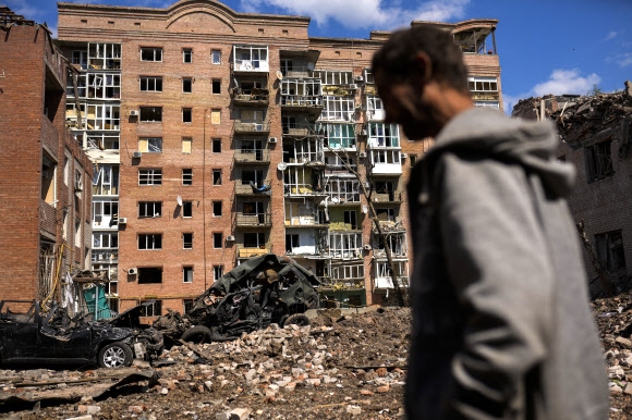 우크라이나 동부 도네츠크주 바흐무트에서 한 남자가 러시아군의 공격으로 심하게 파손된 건물과 파괴된 차량들 앞을 걸어가고 있다. 2022.5.24 AP 연합뉴스