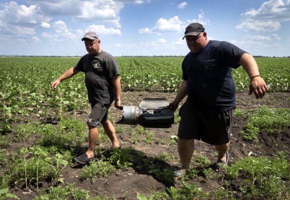우크라이나 도네츠크주의 한 해바라기밭에서 농부들이 러시아 로켓 파편을 걷어내고 있다. 2022.6.21 AP 연합뉴스