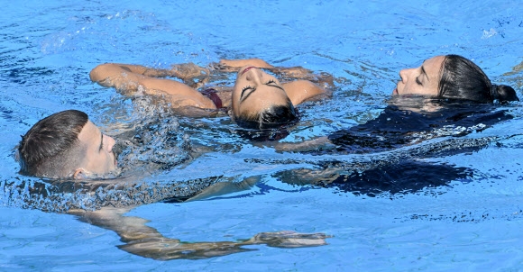 미국 아티스틱스위밍 알바레스(가운데)가 물속에서 의식을 잃자 푸엔테스(오른쪽) 코치가 물속에 뛰어 들어 구조하고 있다. EPA연합뉴스