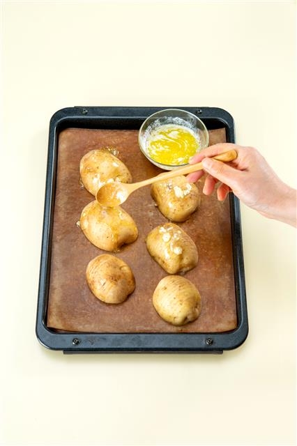 3. 오븐 팬에 칼집을 낸 감자를 얹고 마늘 버터 소스를 골고루 뿌린 다음 180도로 예열한 오븐에서 25분 정도 굽는다.