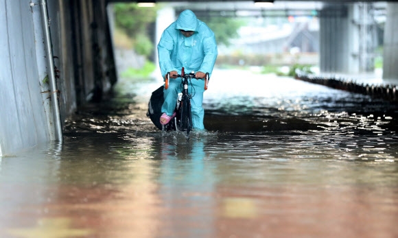 새벽부터 폭우가 쏟아진 30일 오전 침수된 서울 은평구 불광천에서 시민이 물에 반쯤 잠긴 자전거를 타고 이동하고 있다. 2022.06.30. 뉴시스