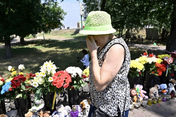 우크라이나 중부 폴타바주 크레멘추크시의 쇼핑몰 옆에 놓인 어린이 장난감과 꽃 앞에서 한 여성이 얼굴을 감싼 채 흐느끼고 있다. 지난 27일(현지시간) 러시아군의 미사일 공격으로 쇼핑몰이 파괴됐고 최소 18명이 사망했다. 2022.6.29 AFP 연합뉴스