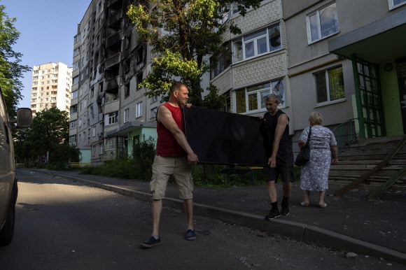 2022년 7월 1일 금요일 우크라이나 하르키우에서 발생한 러시아군의 공격으로 피해를 입은 남성들이 집에서 평면 TV를 들고 나오고 있다. 2022.07.01 AP뉴시스
