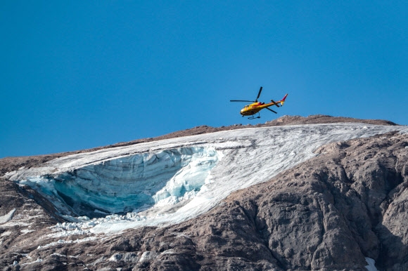 이탈리아 구조 헬리콥터가 전날 돌로미티의 최고봉 마르몰라다 봉우리의 빙하 덩어리가 떨어져나가 적어도 7명의 목숨을 앗은 눈사태 현장 상공을 4일 선회하며 실종자 흔적을 찾고 있다. AFP 연합뉴스