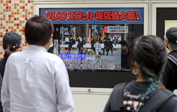8일 일본 도쿄 거리에서 시민들이 아베 신조 전 총리의 피격 소식을 전하는 TV 뉴스를 보고 있다.  AP·교도 연합뉴스
