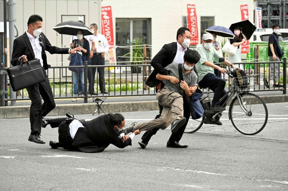 일본 아사히 신문이 8일 아베 신조 전 총리에게 총격을 가해 죽음에 이르게 한 용의자 야마가미 데츠야를 체포하는 과정에 경호원이 넘어지는 와중에도 바지가랑이를 잡고 있는 순간을 포착했다. 아사히 신문 제공 AFP 연합뉴스
