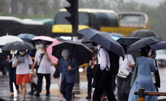 비가 내린 13일 서울 광화문사거리 인근에서 시민들이 우산을 쓰고 걸어가고 있다.