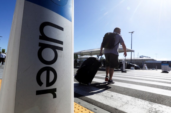 한 남성이 미국 캘리포니아주 로스앤젤레스 국제공항(LAX) 앞 우버 간판 근처를 지나고 있다. 사진은 기사 내용과 무관함. 2022.7.10 로이터 연합뉴스
