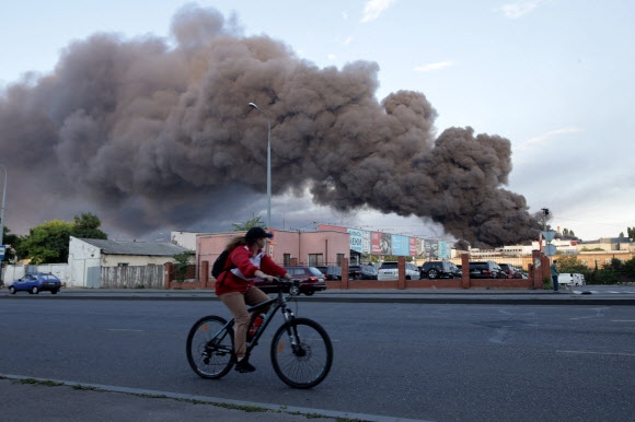 16일(현지시간) 오데사의 한 무역회사 창고가 미사일 공격을 받은 가운데 자전거를 탄 여성이 화재로 인한 연기 구름 앞을 지나고 있다. 사진은 기사 내용과 무관함. 2022.7.16 AFP 연합뉴스