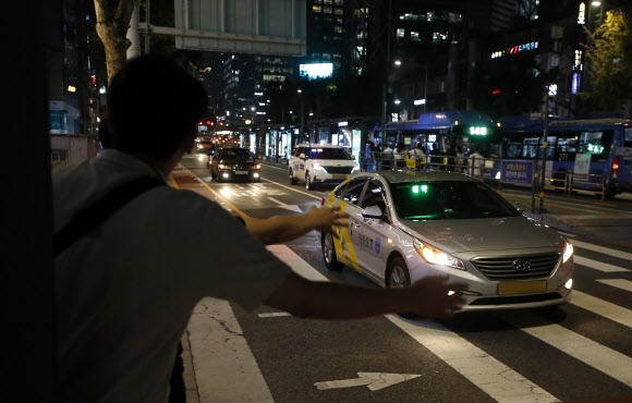 정부가 심야시간대 택시 승차난을 완화하기 위해 합승 서비스를 도입했지만 25일 현재 합승 서비스 제공을 신청한 사업자가 한 곳도 없다. 사진은 지난 19일 밤 서울 도심에서 시민들이 택시를 잡는 모습. 뉴시스