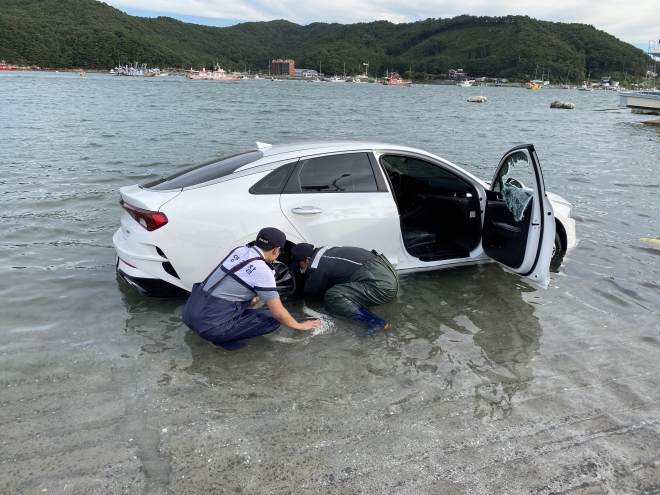 보령시 오천항 선창에 세워놨다 밀물에 침수된 승용차를 해경 등이 밖으로 끌어내려고 애쓰고 있다. 보령해양경찰서 제공