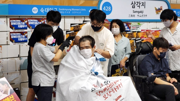 전국장애인차별철폐연대(전장연) 관계자들이 3일 서울 용산구 4호선 삼각지역 승강장에서 장애인 권리 예산 보장을 촉구하며 삭발 시위를 벌이고 있다. 2022.8.3  연합뉴스