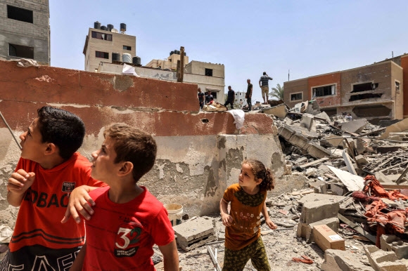 이스라엘군이 6일(현지시간) 팔레스타인 가자지구 남부 칸 유니스에 폭격을 가하자 어린이들이 깜짝 놀라며 폭격이 터진 곳으로 추정되는 곳을 바라보고 있다. 가자지구 AFP 연합뉴스