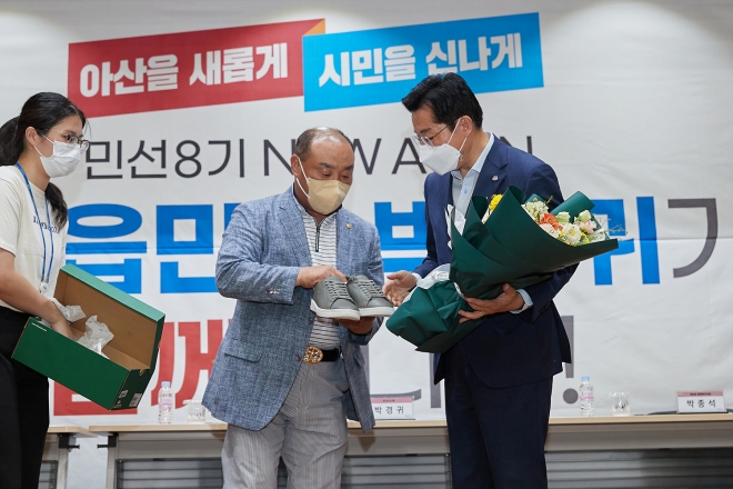 박경귀 아산시장이 읍면동 방문현장에서 시민으로부터 발로 뛰어달라 신발을 선물 받고 있다. 사진=아산시 제공)