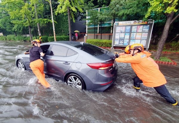 인천지역에 폭우가 내린 8일 인천시 미추홀구 용현동 한 도로에서 소방대원들이 침수된 차량을 안전한 곳으로 옮기고 있다. 연합뉴스