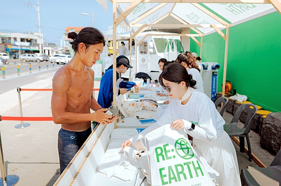 지난 6·7일 제주 월정리 해변에서 열린 1차 ‘리얼스 마켓(RE:EARTH MARKET)’ 참가자들이 장갑과 집게로 이뤄진 비치코밍 용품을 대여하고 있다. 롯데백화점 제공