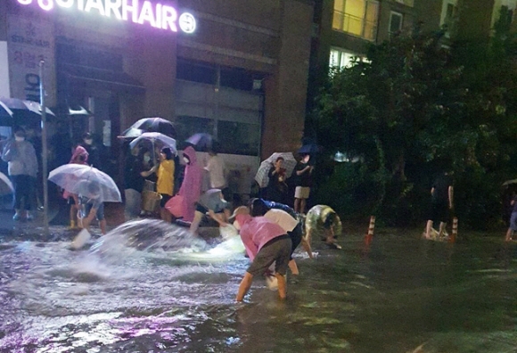 10일 폭우가 내린 충북 청주시 흥덕구 복대동의 한 아파트 주민들이 지하주차장 침수를 막기 위해 직접 나서 빗물을 퍼내고 있다. 트위터 캡쳐