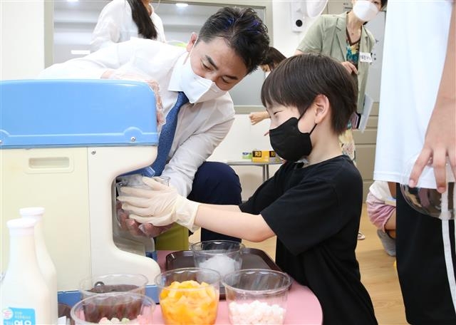 오언석(왼쪽) 서울 도봉구청장이 쌍문동에 있는 우리동네키움센터 5호점에서 한 아이에게 팥빙수에 사용할 얼음을 그릇에 담아 주고 있다. 도봉구 제공