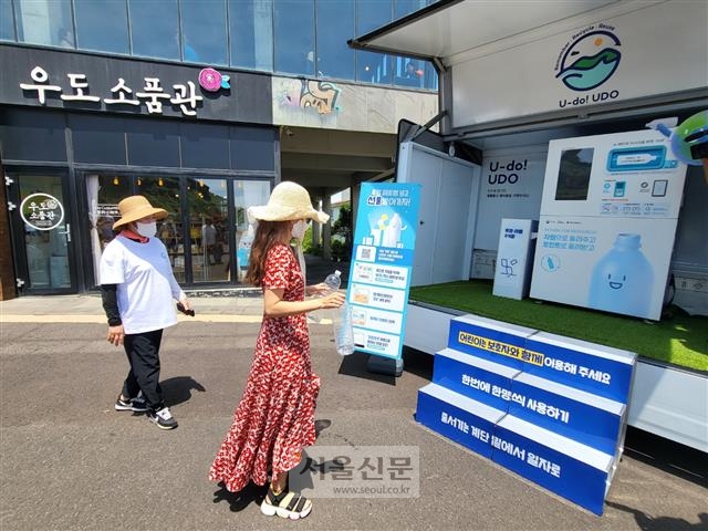 우도에 여행 온 한 관광객이 검멀레동굴 근처 우도소품관 앞에 설치된 이동식 페트병 반납기에 플라스틱 병을 반납하러 가고 있다.