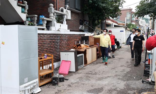 박일하(왼쪽) 서울 동작구청장이 지난 11일 집중호우로 피해를 본 사당동 한 주택가를 방문해 주민의 애로사항을 청취한 후 후속 대책에 관해 설명하고 있다. 동작구 제공