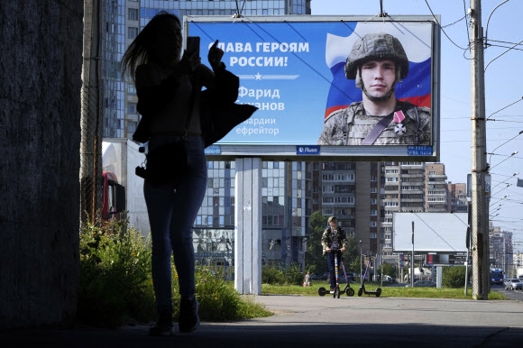 러시아 상트페테르부르크에서 한 여성이 ‘러시아의 영웅들에게 영광을’이라는 문구가 적힌 광고판 앞을 지나고 있다. 2022.8.20 AP 연합뉴스