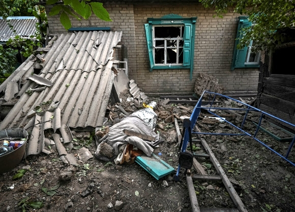 러시아군의 로켓 공격으로 파괴된 우크라이나 드니프로페트로우스트주 채플린의 주탁가에 이번 공격으로 사망한 11세 소년의 시신이 천 등으로 덮여 있다. 2022.8.24 로이터 연합뉴스