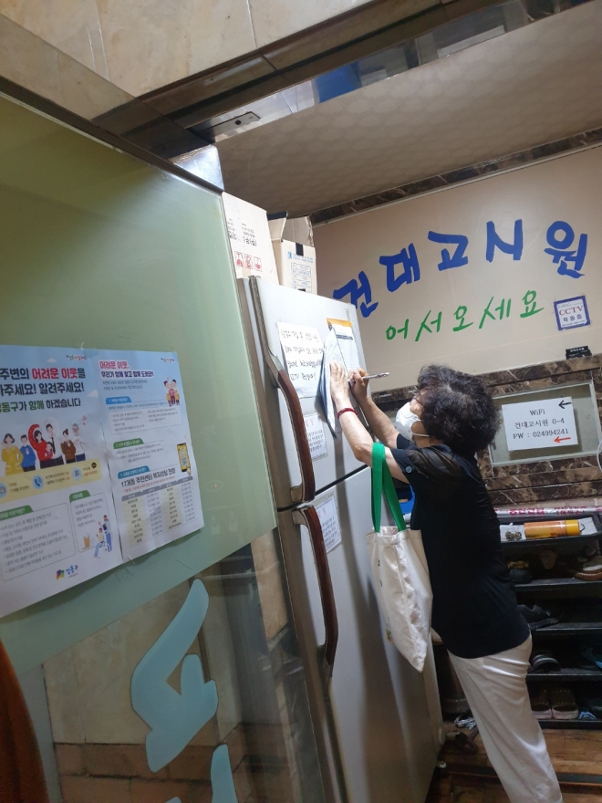 지난 2월 첫 활동을 시작한 서울 성동구 ‘중장년 돌봄 전담 인력’이 지역의 한 고시원을 방문해 안내문을 작성하고 있다. 성동구 제공