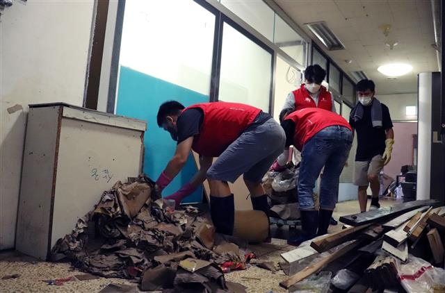 롯데정보통신 직원들이 지난 12일 집중호우로 큰 피해를 입은 서울 금천구 일대의 상가들을 찾아 폐기물 정리 등 수해복구 작업을 하고 있다. 롯데 제공