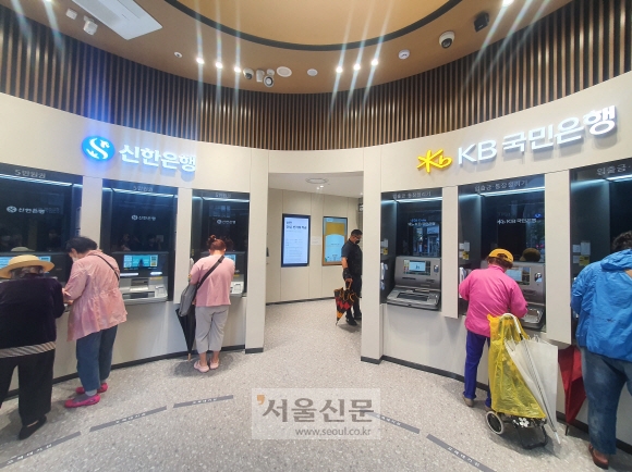 5일 경기 양주시에 있는 KB국민·신한은행 공동점포를 방문한 고객들이 현금자동입출금기(ATM)를 이용하고 있다. 같은 공간에 신한은행(왼쪽)과 국민은행의 ATM이 함께 설치돼 있는 모습.