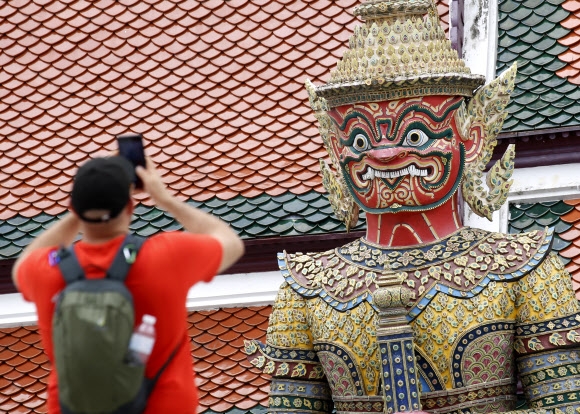 한 관광객이 태국 방콕의 에메랄드 사원(왓 프라께오)의 거대한 조각상 앞에서 사진을 찍고 있다. 2022.9.5 EPA 연합뉴스