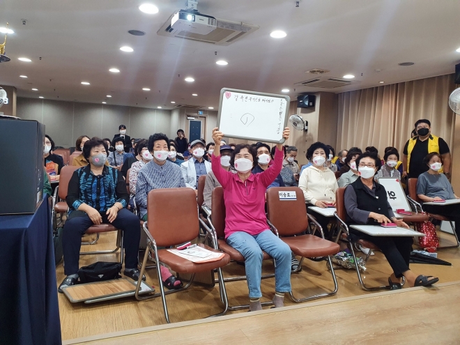 서울 성북구립석관실버복지센터가 어르신들을 위해 마련한 ‘제3회 두뇌장사대회’의 모습. 최종 우승자인 김숙연(76)씨가 마지막 문제의 정답이 적힌 칠판을 들어 보이고 있다. 성북구 제공 