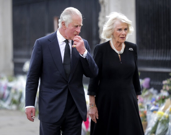 영국 새 국왕 찰스 3세와 왕비 커밀라가 9일(현지시간) 영국 런던의 버킹엄 궁전 밖에 시민들이 두고 간 추모 꽃다발들을 보고 있다. EPA 연합뉴스