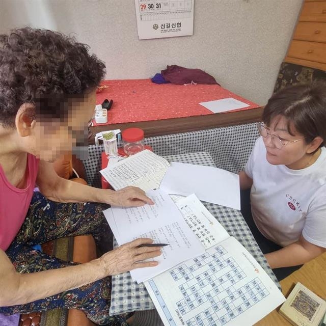 ‘전화는 기억을 싣고 봉사단’ 회원(오른쪽)이 독거 치매 어르신에게 인지활동 보조 봉사 활동을 하고 있다. 영등포구 제공