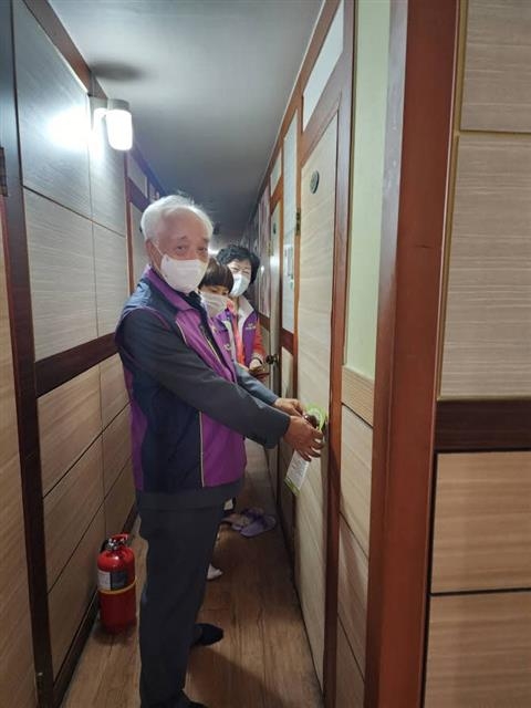 서울 성북구 종암동 지역사회보장협의체 회원과 생명의전화종합사회복지관 직원들이 한 고시원을 찾아 방문에 홍보 안내문을 걸고 있다. 성북구 제공