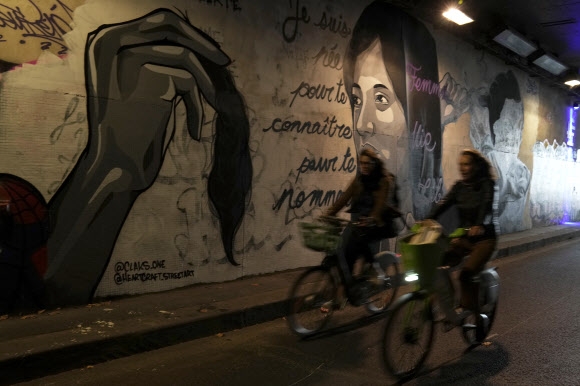 5일(현지 시간) 프랑스 파리의 한 터널에 여성들이 권력에 맞서기 위해 머리카락을 자르는 것을 묘사한 벽화 앞을 여성들이 자전거를 타고 지나고 있다. 벽화에는 “여성 삶의 자유” 등의 내용이 쓰여 있다. 파리 AP통신 연합뉴스