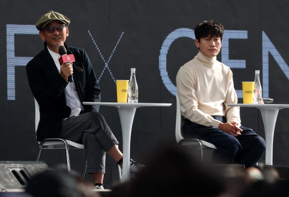 이준익(왼쪽) 감독이 7일 부산 해운대구 영화의전당 야외무대에서 열린 제27회 부산국제영화제(BIFF) ‘온 스크린’에 참여한 티빙의 오리지널 시리즈 ‘욘더’ 오픈토크 도중 작품을 소개하는 것을 주연 신하균이 귀기울이고 있다. 부산 연합뉴스 