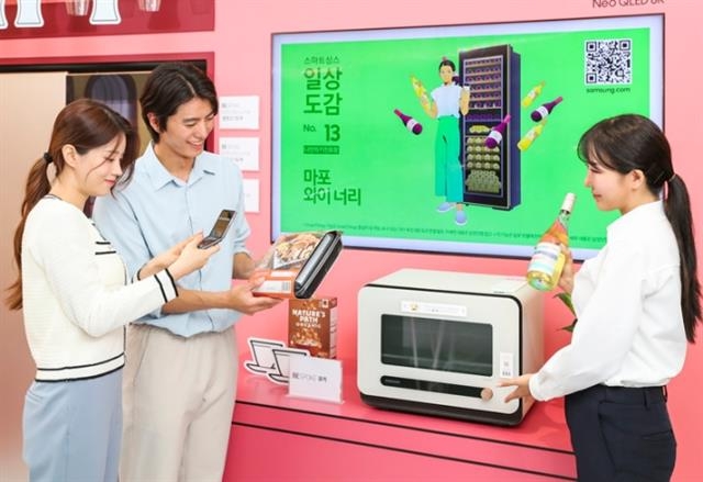 삼성전자 모델들이 지난 7일 서울 코엑스 ‘한국전자전 2022’ 행사장에 마련된 전시 공간에서 ‘비스포크 큐커’와 함께 와인과 어울리는 밀키트까지 추천해 주는 스마트싱스의 ‘소믈리에 앳 홈’ 기능을 소개하고 있다.  삼성전자 제공