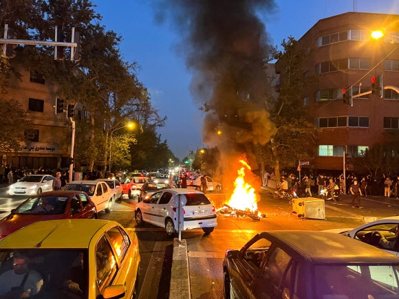 지난달 19일(현지시간) 마흐사 아미니의 죽음에 항의하는 이란 테헤란 시위 현장에서 오토바이가 불에 타고 있다. 약 한 달째를 맞는 시위에서는 당국의 탄압으로 최소 201명이 숨진 것으로 나타났다. 테헤란 로이터 연합뉴스