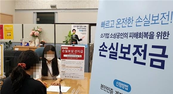 소상공인시장진흥공단의 서울중부지역센터에서 직원이 한 소상공인에게 코로나19 위기 극복을 위한 손실보전금에 대해 설명하고 있다. 소진공 제공