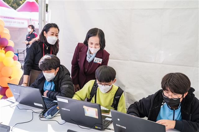 이수희 서울 강동구청장이 지난 20일 진로직업박람회 직업 체험 부스에 참여한 청소년들과 함께하고 있다. 강동구 제공