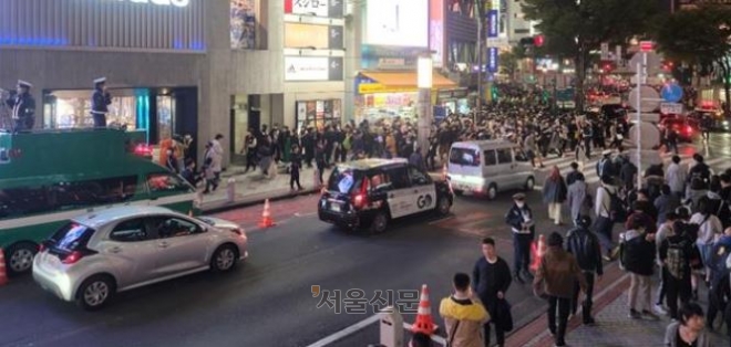 지난달 31일 핼러윈축제가 벌어진 일본 도쿄 시부야 번화가 모습. 경찰(왼쪽)이 개조 차량 위에 올라가 확성기를 통해 인파를 분산시키고 있다. 도쿄 김진아 특파원