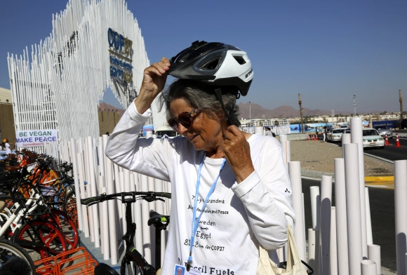 12일(현지시간) 환경운동가 도로시 힐데브란트(72)가 이집트 샤름 엘 셰이크의 유엔 기후정상회의(COP27) 회의장 앞에서 자전거 헬멧을 벗고 있다. 그는 기후 위기를 막기 위해 세계 지도자들이 나서야 한다고 촉구하기 위해 ‘자전거 퍼포먼스’를 벌였다. 샤름 엘 셰이크 AP 연합뉴스