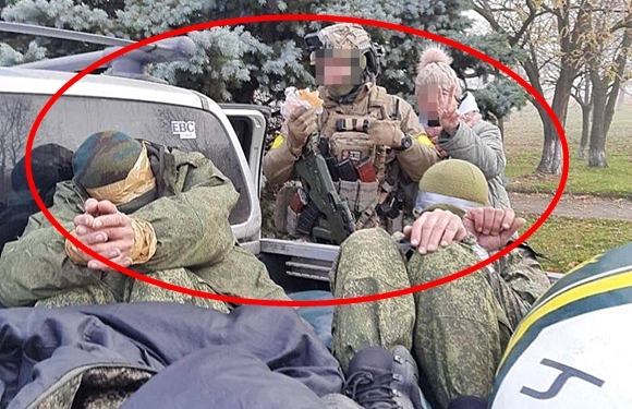 한 우크라이나군 병사와 주민이 탈환한 남부 요충지 헤르손에서 포획한 러시아군 포로를 배경으로 웃어 보이고 있다. 포로들은 테이프로 결박된 모습이다. 2022.11.11  우크라이나나우