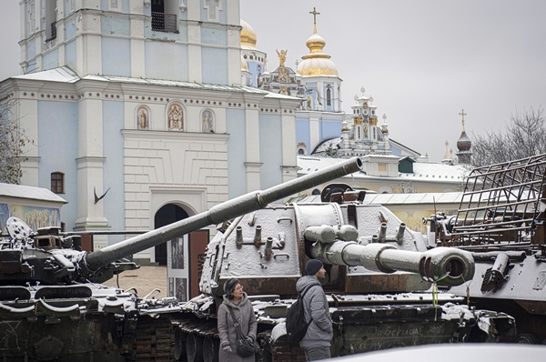 17일(현지시간) 올 겨울 첫눈이 내린 우크라이나 수도 키이우 시내에서 행인들이 파괴된 러시아 탱크와 장갑차 앞을 지나고 있다. 2022.11.17  AP 연합뉴스