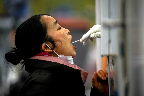 20일 중국 베이징에서 한 여성이 코로나19 핵산 검사를 받고 있다. 베이징에서는 감염병이 재유행하면서 일부 지역에서는 주민들에 24시간 핵산 전수 검사를 의무화하고 있다. 베이징 AFP 연합뉴스