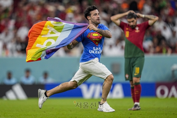 H조 - 포르투갈 대 우루과이 - 루사일 스타디움, 카타르, 루사일 - 2022년 11월 28일 경기 도중 이란 여성을 응원하는 셔츠를 입은 관중이 무지개 깃발을 들고 그라운드를 달리고 있다. . (AP Photo/Abbie Parr)