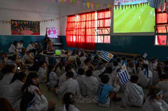 우루과이 초등학생들이 2022년 11월 28일 몬테비데오에 있는 학교에서 열린 2022년 월드컵 H조 우루과이와 포르투갈의 축구 경기를 생중계로 시청하고 있다. (Photo by Eitan ABRAMOVICH / AFP)
