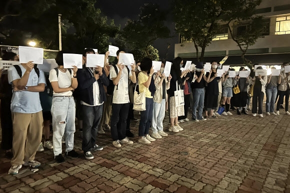 중국의 ‘제로 코로나’ 정책에 항의하는 ‘백지(白紙)시위’를 지지하는 연대 시위가 세계 곳곳에서 벌어졌다. 홍콩의 대학생들이 우루무치 화재 희생자들을 추모하며 백지를 들어 보이고 있다. 홍콩 AP 연합뉴스
