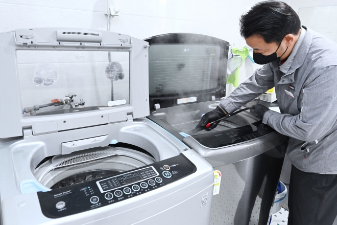 LG전자 직원이 사회복지시설에서 세탁통에 스팀을 분사하는 통살균 서비스를 진행하고 있다. LG전자 제공 