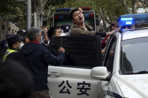 In this photo taken on Sunday, 중국의 ‘제로 코로나’ 정책에 지친 애플이 대중 의존도를 대폭 줄이는 ‘탈(脫)중국’ 계획을 가속화하는 것으로 알려졌다. 사진은 지난달 27일 베이징에서 제로코로나 정책에 항의하던 상하이 시민이 경찰에 연행되는 모습  상하이 AP 뉴시스